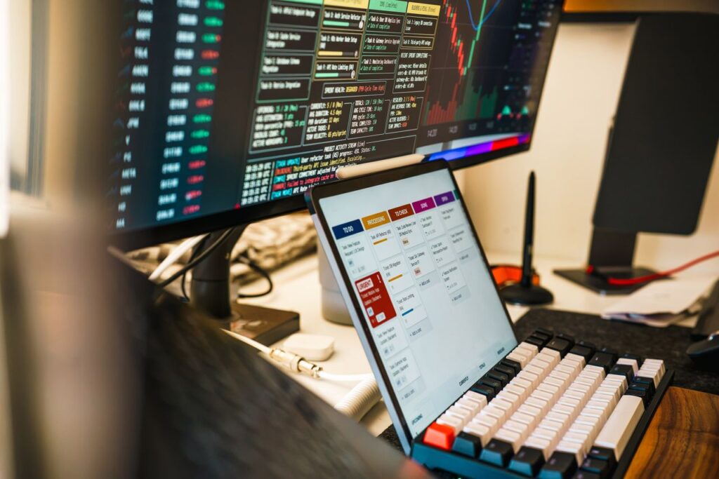 A sleek, modern workspace featuring trading monitors and a tablet for project management.