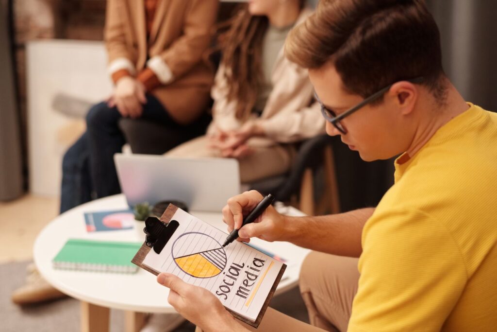 Young professional reviewing social media strategy in a modern office setting with collaborators.